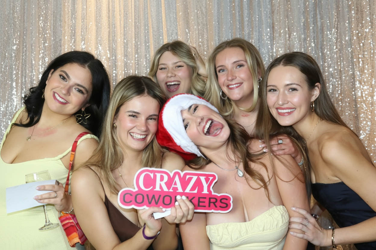 Guests crowding into frame with a 'crazy coworkers' sign at a holiday party